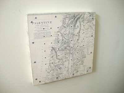 Photo of Ken kalman's sculpture "Counting the Omar." Artwork depicts a map of Palestine with holes and pegs.