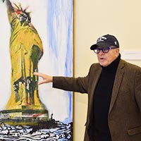 A photo of George Krevsky discussing an artwork depicting the Statue of Liberty.