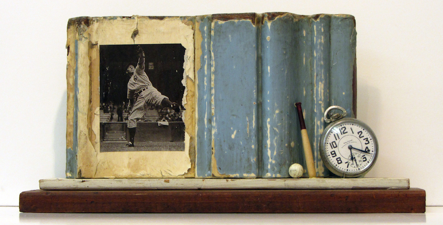 Photo of Stacey Carter's assemblage sculpture "Yankee Pitch." Artwork depicts a shelf with blue partial frame, a photo of a baseball pitcher, a small ball and bat and a watch.