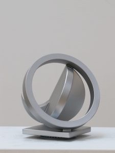 Fletcher Benton's sculpture of silver colored circle with a folded circle design in the center.