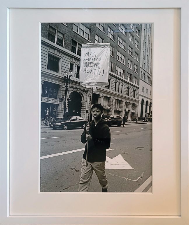 Photo of Richard Nagler's photograph "Make America Think Again." Artwork depicts a person protesting with a sign that says Make America Think Again.