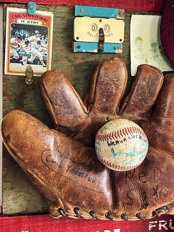 Close up of an old  baseball mitt, baseball, and baseball card from Kat Flyn's Teddy sculpture.