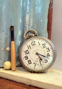 Close up of a watch and a small baseball and bat from Stacey Carter's Yankee Pitch sculpture.