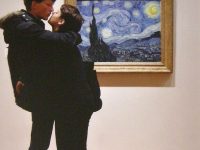 Color photograph of a couple embracing in front of Van Gogh's Starry Night painting.