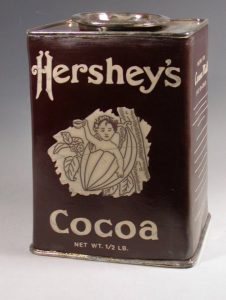 Ceramic replica of a vintage brown Hershey's chocolate tin with a logo of a child in a cocoa bean
