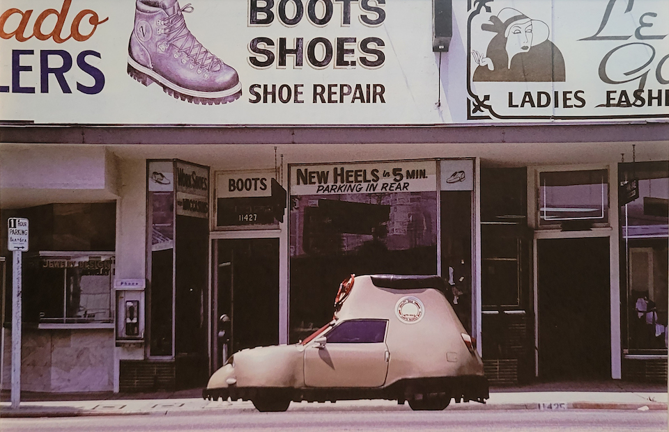 Color photograph of a shoe store's exterior with a shoe shaped car parked in front