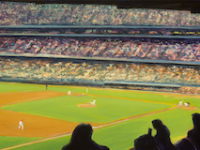 Photo of David Cooke's painting "Night Game." Artwork depicts a baseball game from the perspective of up in the stands.