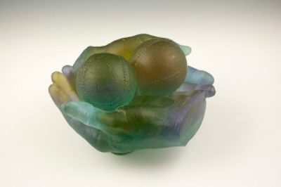 Photo of Milt Friedly's cast crystal sculpture "Coveted Foul Ball -2." Artwork depicts two hands cradling two baseballs.