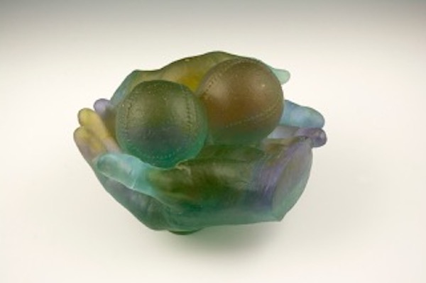 Photo of Milt Friedly's cast crystal sculpture "Coveted Foul Ball -2." Artwork depicts two hands cradling two baseballs.