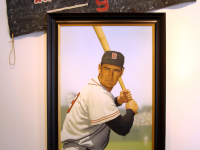 Photo of Arthur K. Miller's painting "Ted Williams at Fenway." Artwork depicts Williams at bat. A separate banner is angled above the painting.